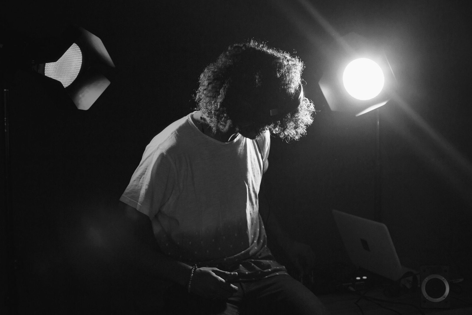 Uomo seduto davanti a un computer portatile, illuminato da faretti da studio, foto in bianco e nero