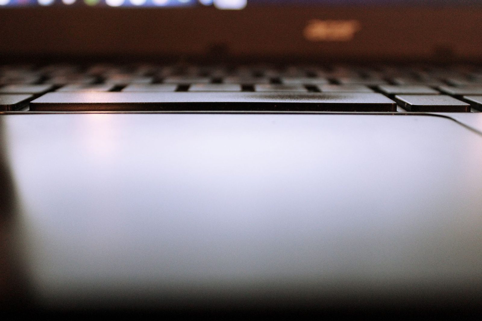 Unscharfe Nahaufnahme von Tastatur und Touchpad eines eingeschalteten Laptops
