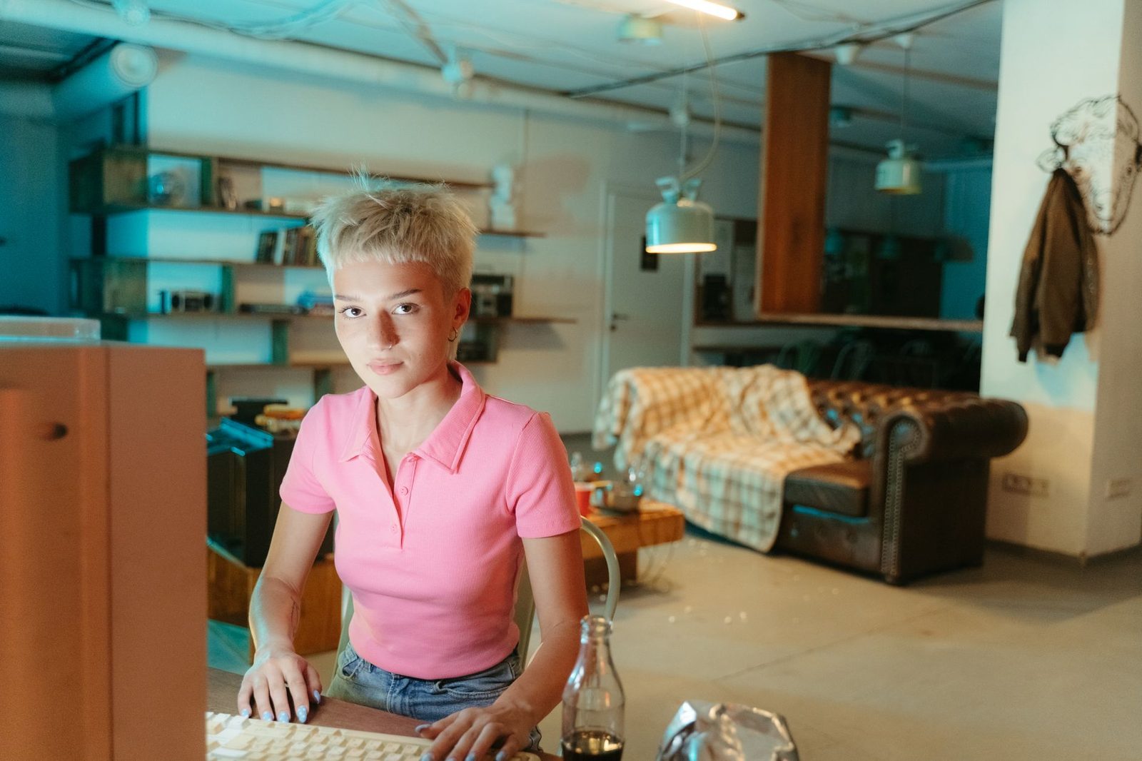 Jeune femme aux cheveux courts blonds devant un clavier d'ordinateur dans un espace de travail